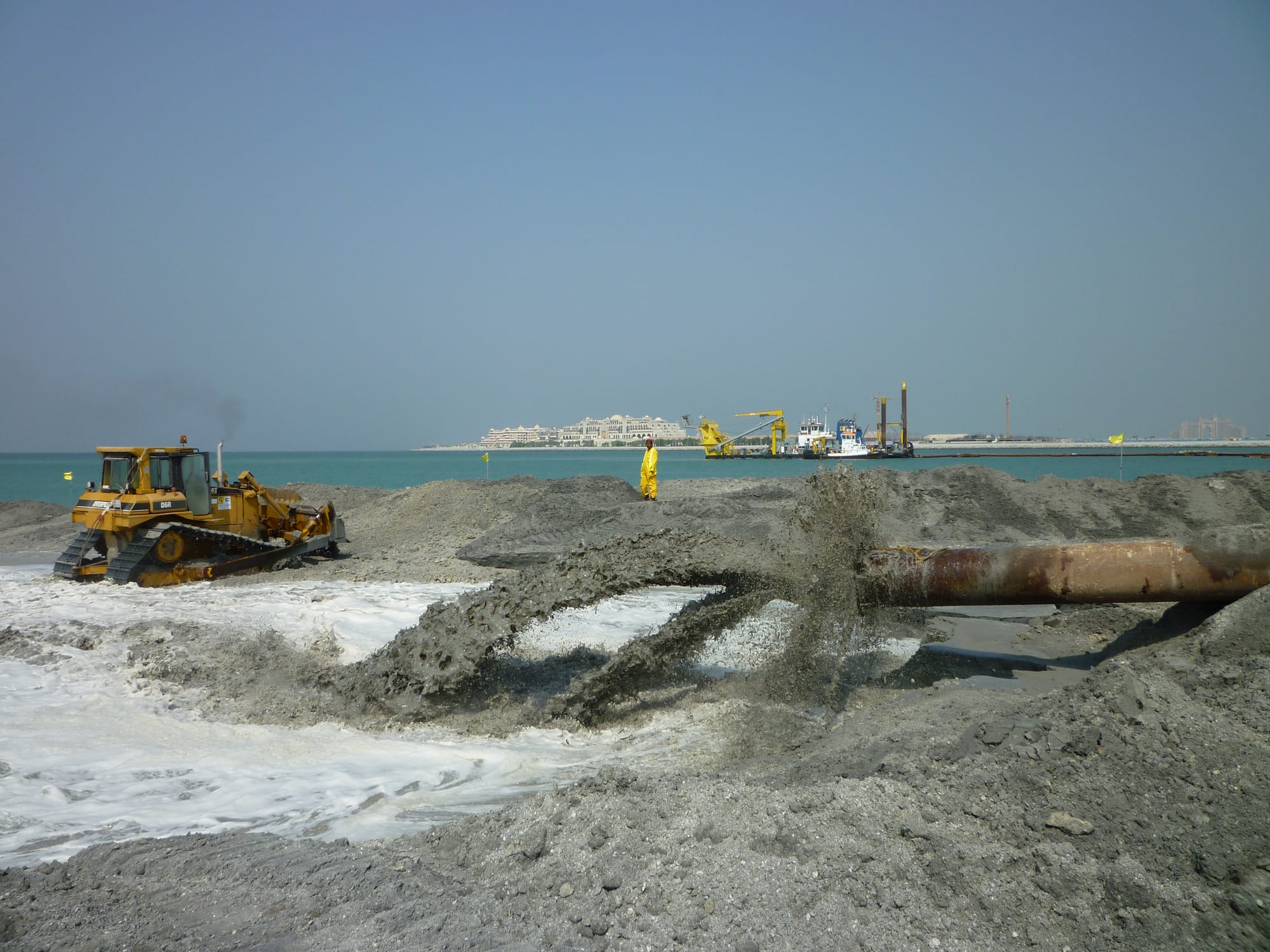 Steel dredge pipeline stacked in the yard with a wheel loader.