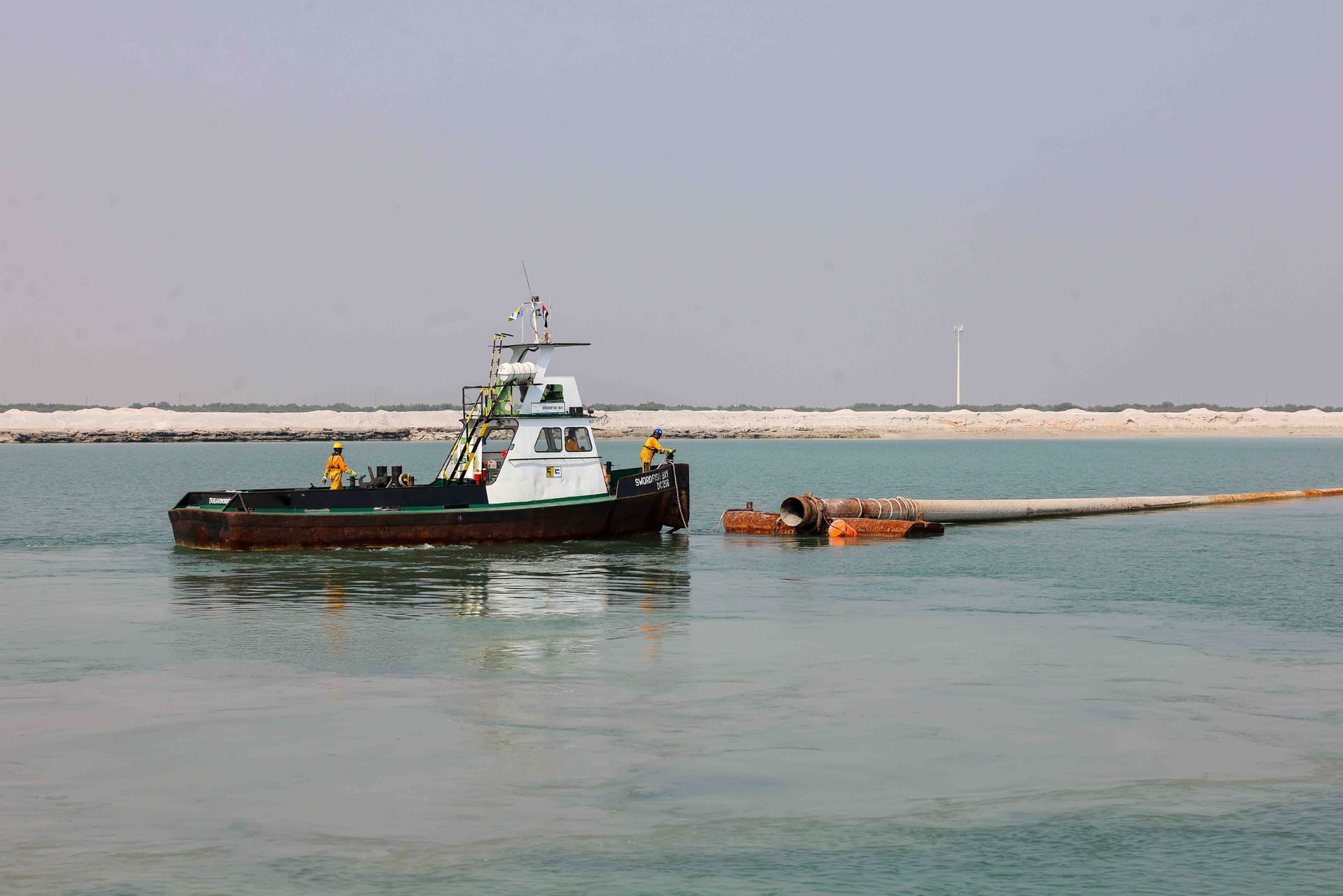 Workboat Swordfish Bay with crew handling the end of a floating dredge discharge pipeline.